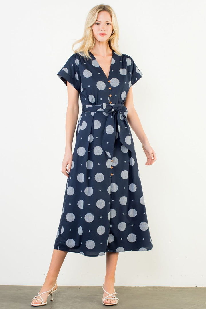 Woman wearing a navy dress with white polka dots against a white background