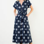 Woman wearing a navy dress with white polka dots against a white background
