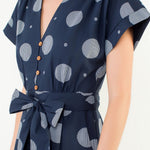 Navy blue dress with gray polka dot pattern worn by a model on a white background
