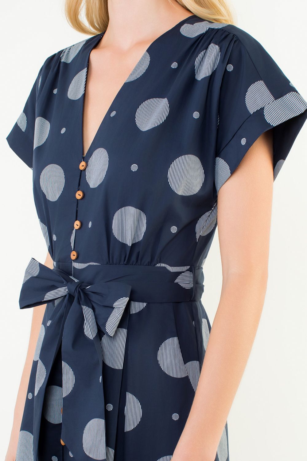 Navy blue dress with gray polka dot pattern worn by a model on a white background