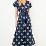 Woman wearing a navy dress with white polka dots against a white background