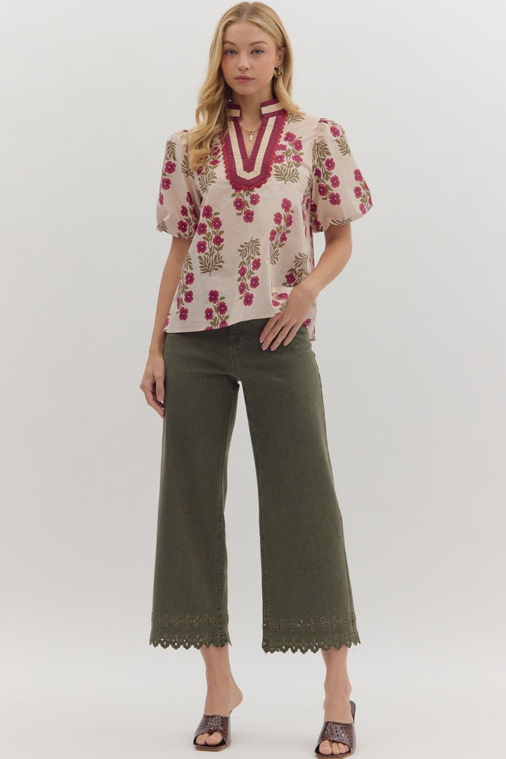 Woman wearing a floral blouse and green pants on a white background