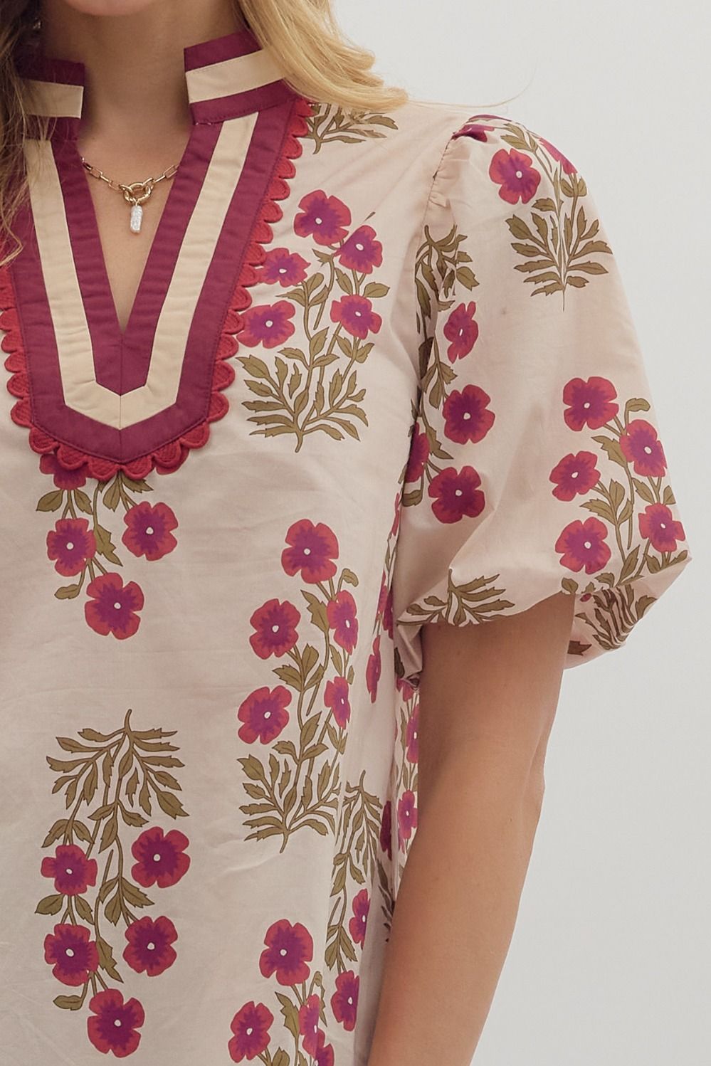 Beige dress with floral patterns and red accents on a plain background