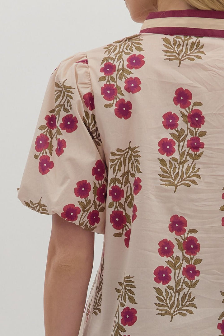 Beige shirt with pink floral patterns on a plain background