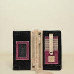 Black clutch with pink accents, zipper, and wrist strap on a white background