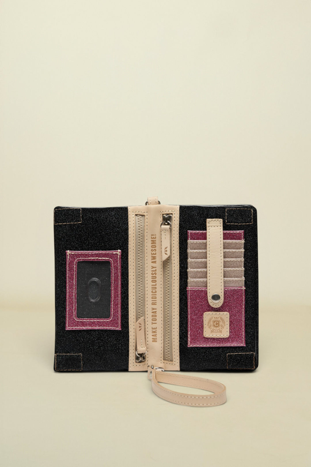Black clutch with pink accents, zipper, and wrist strap on a white background