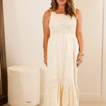 Woman in a white dress standing in a room with a mirror and furniture.