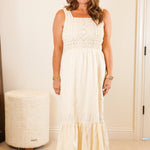 Woman in a white dress standing in a room with a mirror and furniture.