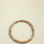 Bracelet with gold and orange beads on a light gray background