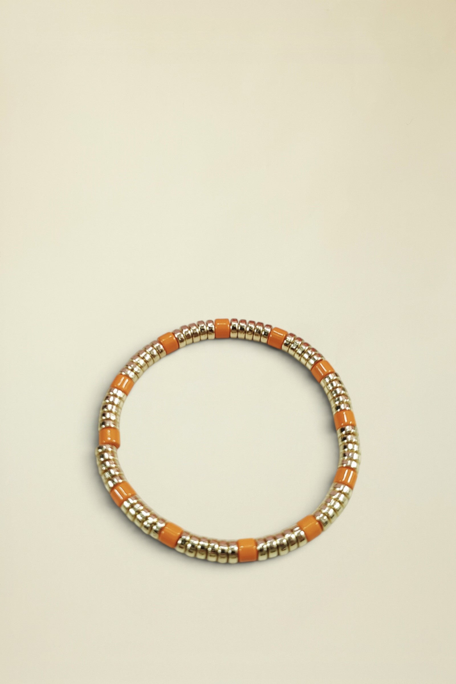 Bracelet with gold and orange beads on a light gray background