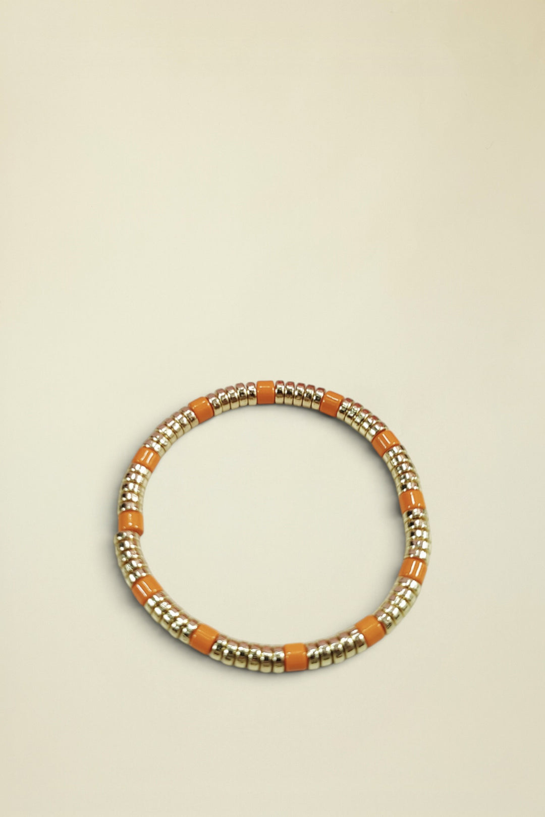 Bracelet with gold and orange beads on a light gray background