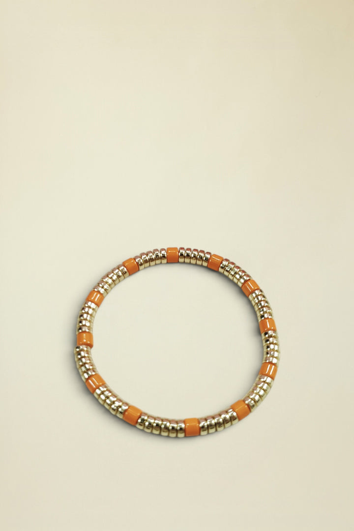 Bracelet with gold and orange beads on a light gray background