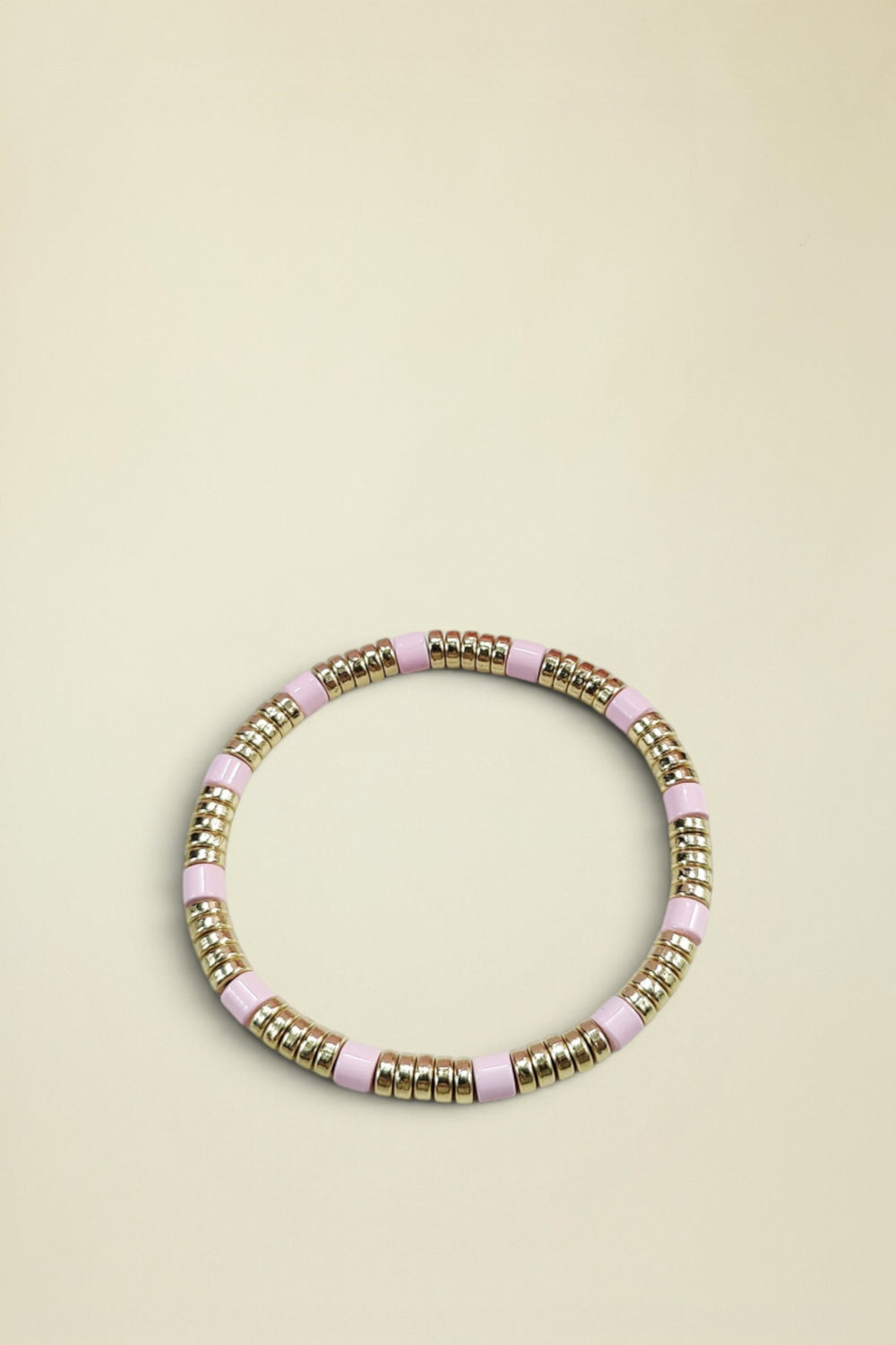 Bracelet with pink and gold beads on a light gray background