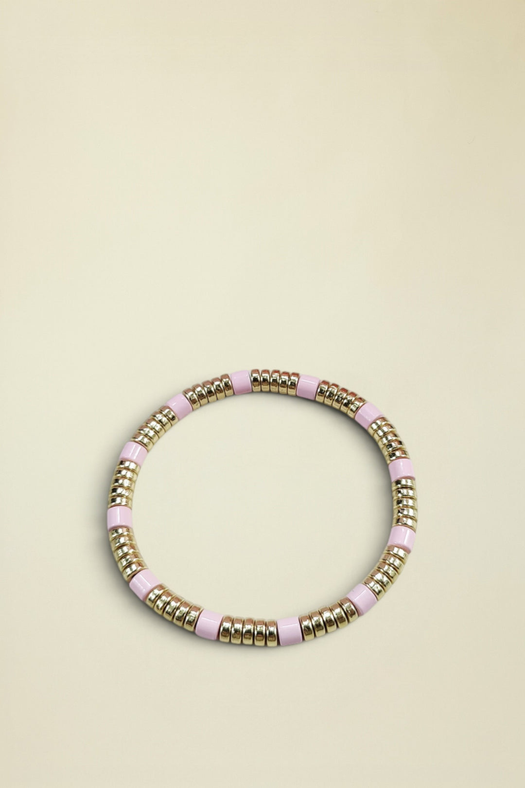 Bracelet with pink and gold beads on a light gray background