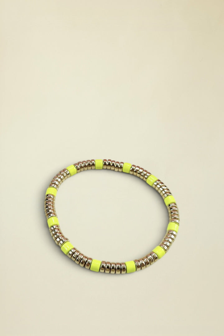 Neon yellow and gold beaded bracelet on a light gray background