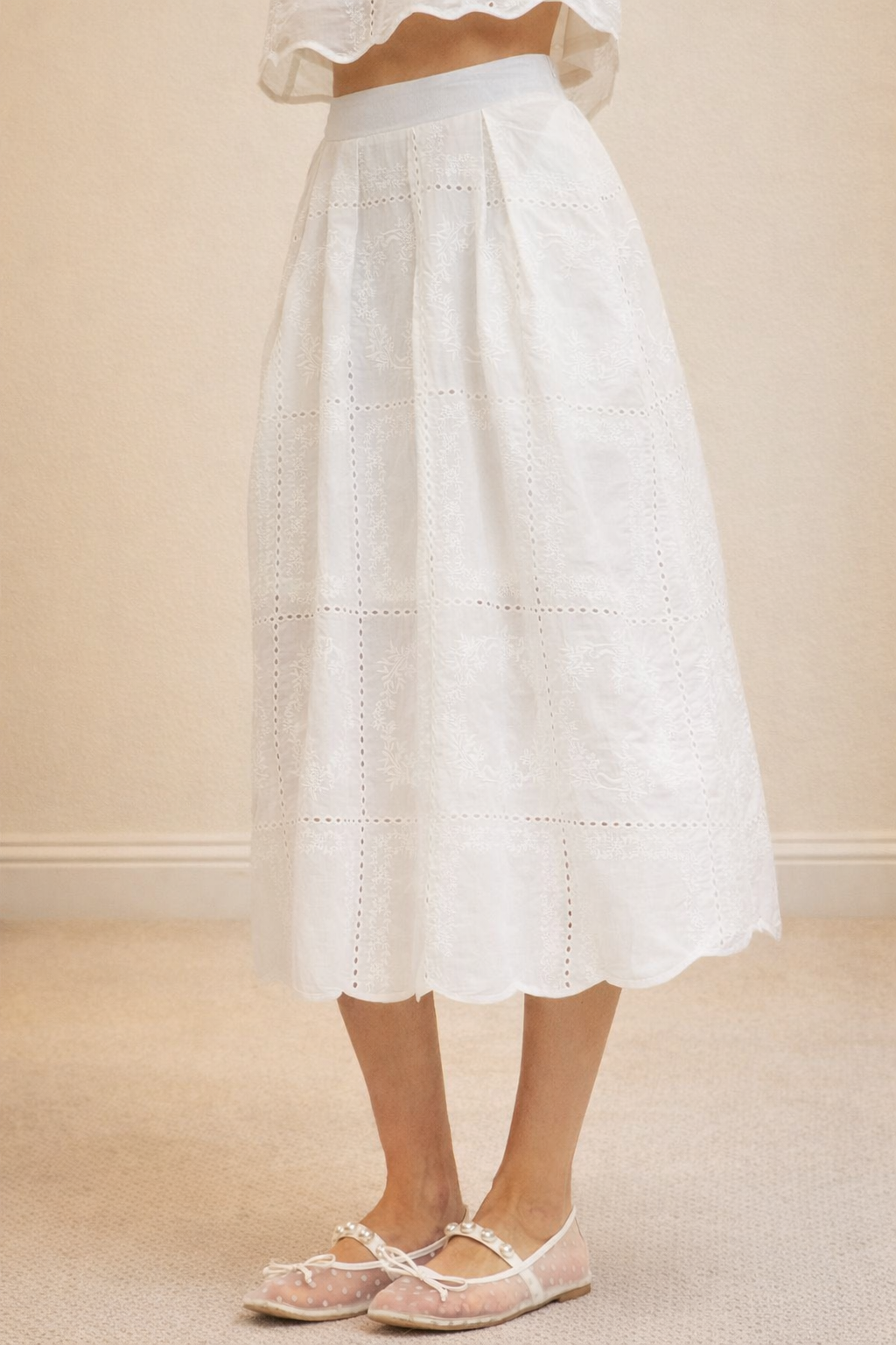 White lace skirt worn by a person on a beige background