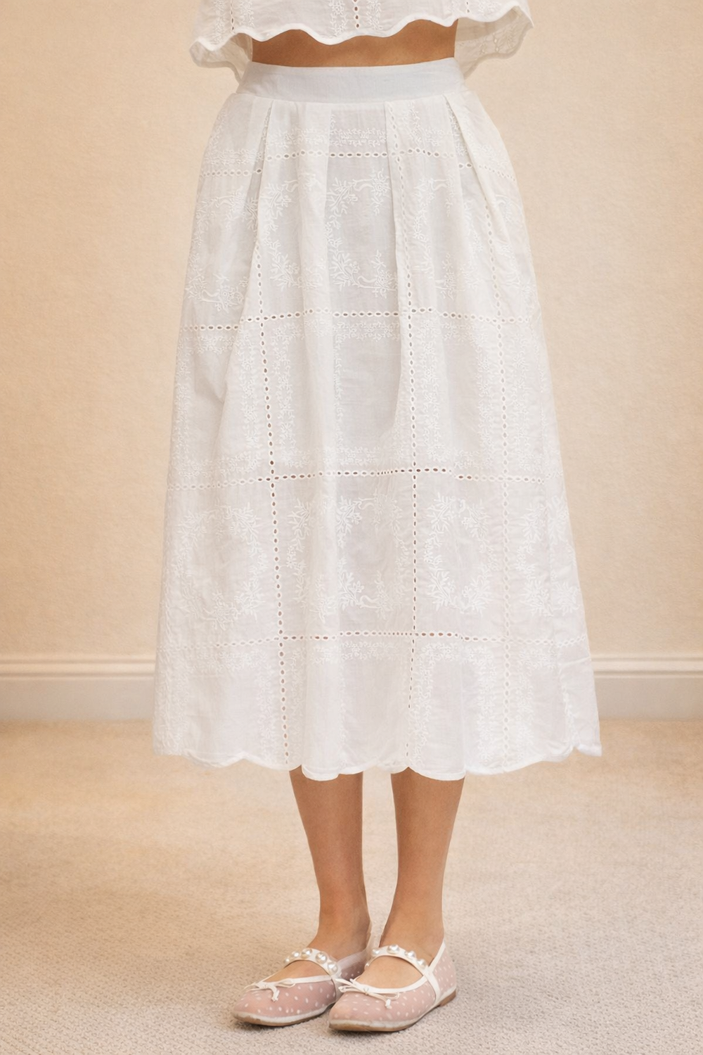 White lace skirt worn by a person on a beige background