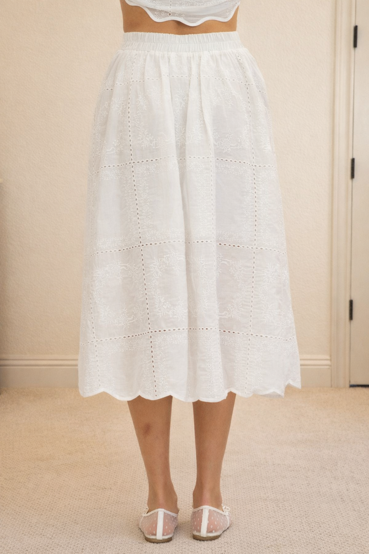White lace skirt worn by a person on a neutral background
