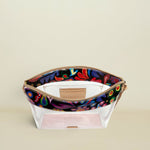 Point of Origin Consuela clear crossbody bag with a glitter base, floral Sophie print trim, and natural leather accents