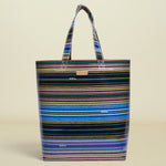 Point of Origin Consuela Hadley basic tote bag featuring a vibrant multi-colored horizontal striped pattern.