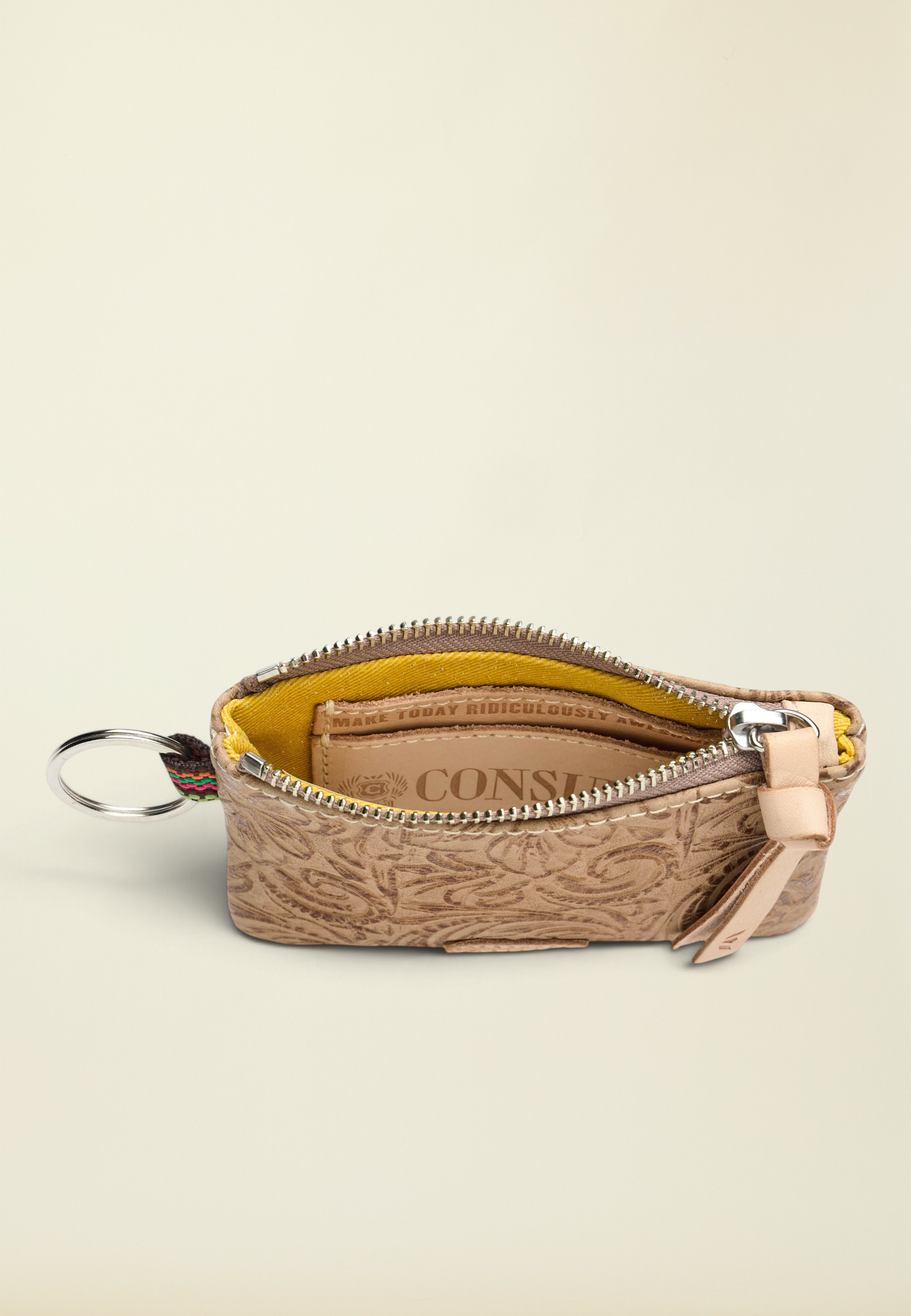 Point of Origin Consuela Lawton pouch in tan tooled leather with a yellow interior, zipper closure, and metal keyring.