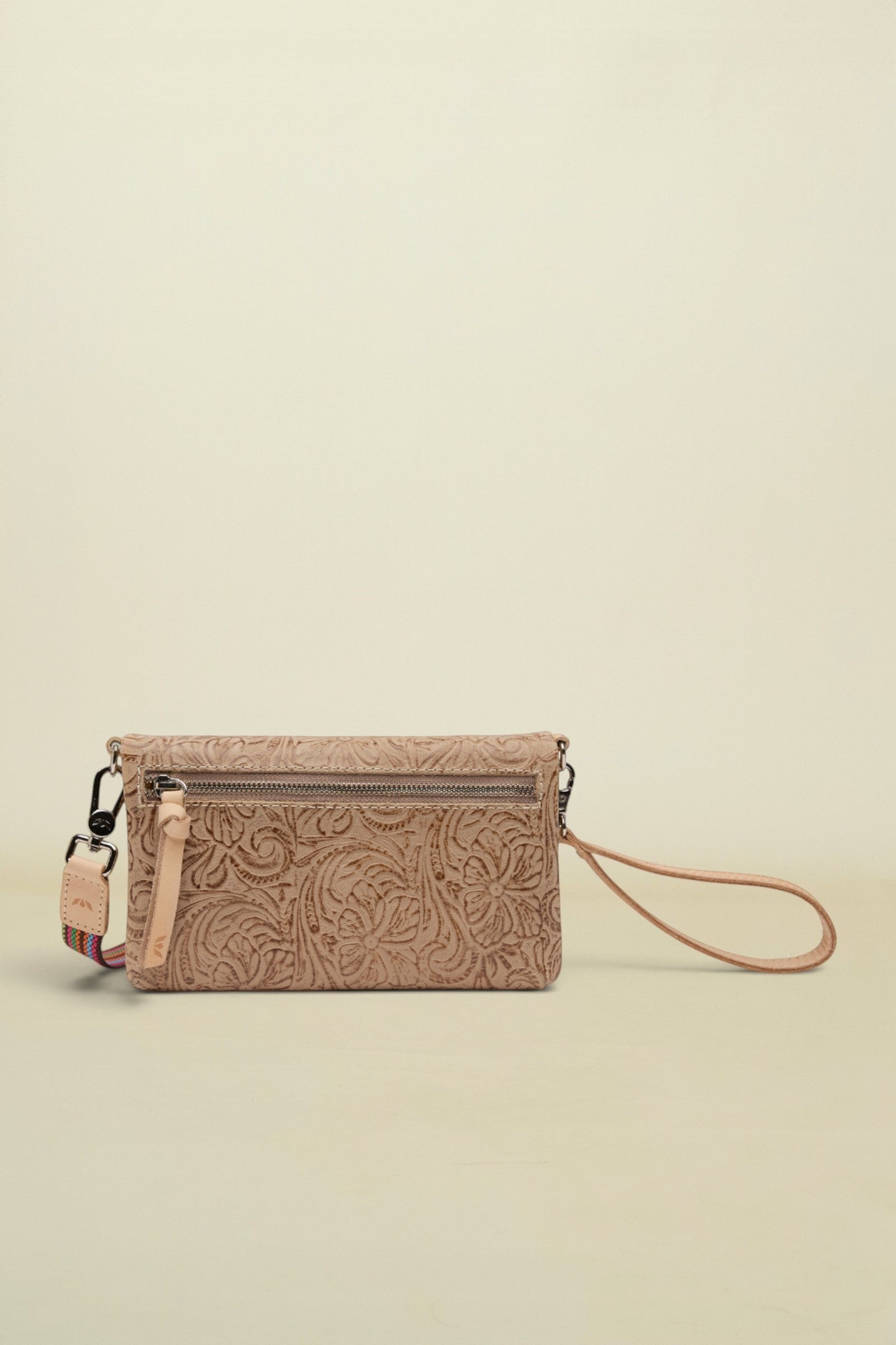 Point of Origin Lawton Uptown crossbody bag in beige leather with intricate floral tooling and a wristlet strap.