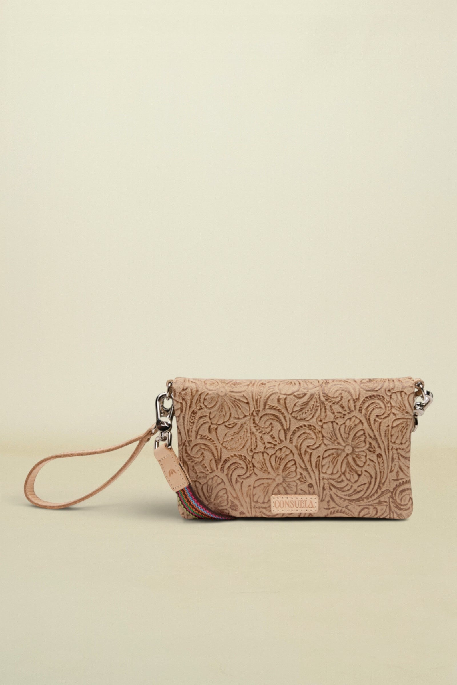 Point of Origin Lawton Uptown crossbody bag in tan embossed leather with a decorative wrist strap.