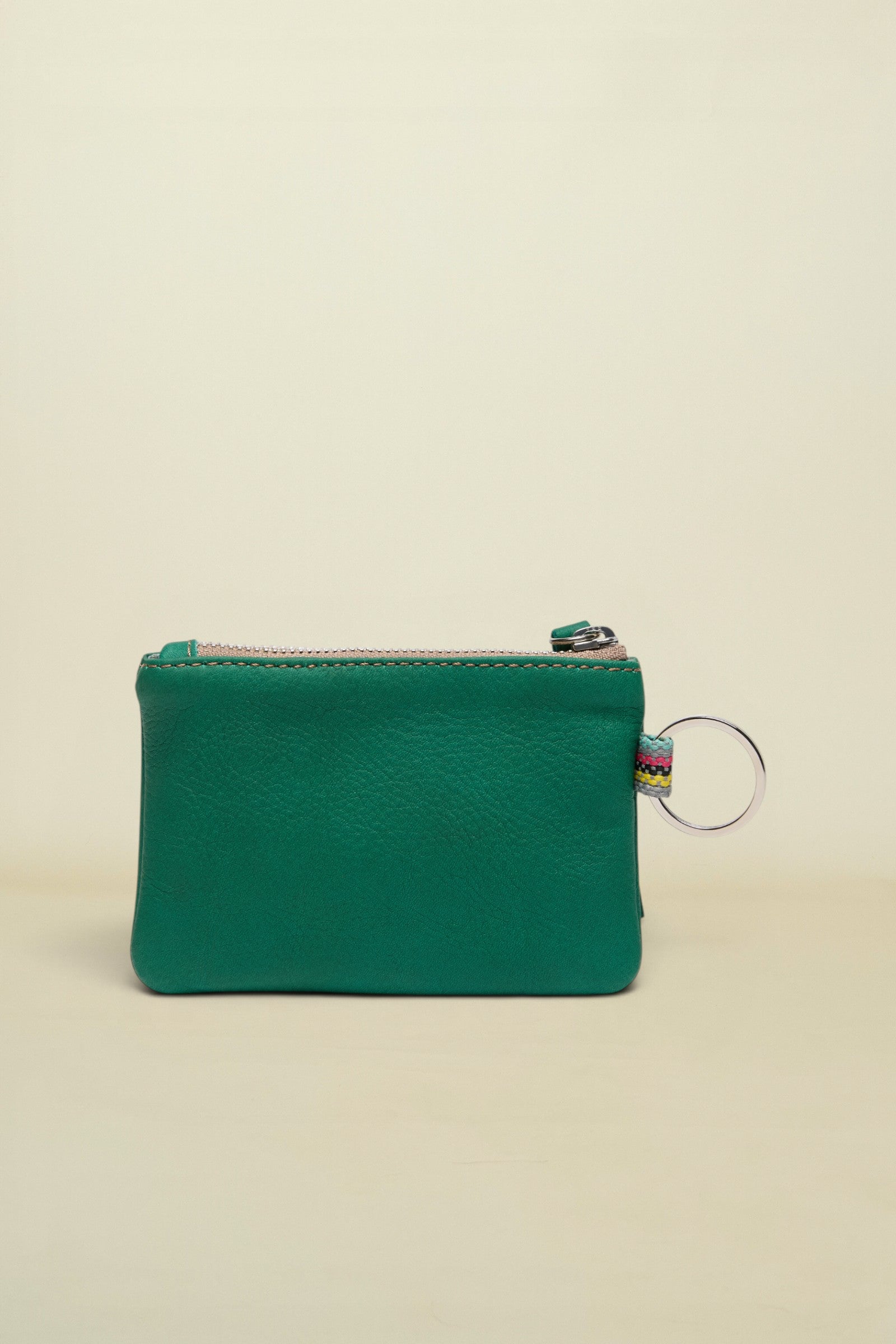 Point of Origin teal leather coin pouch with a silver zipper and a small multi-colored fabric loop with a key ring.