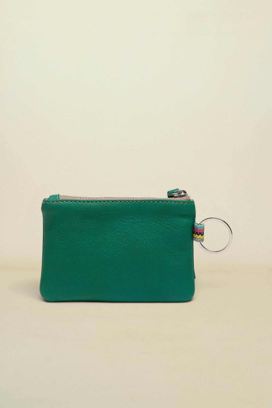 Point of Origin teal leather coin pouch with a silver zipper and a small multi-colored fabric loop with a key ring.