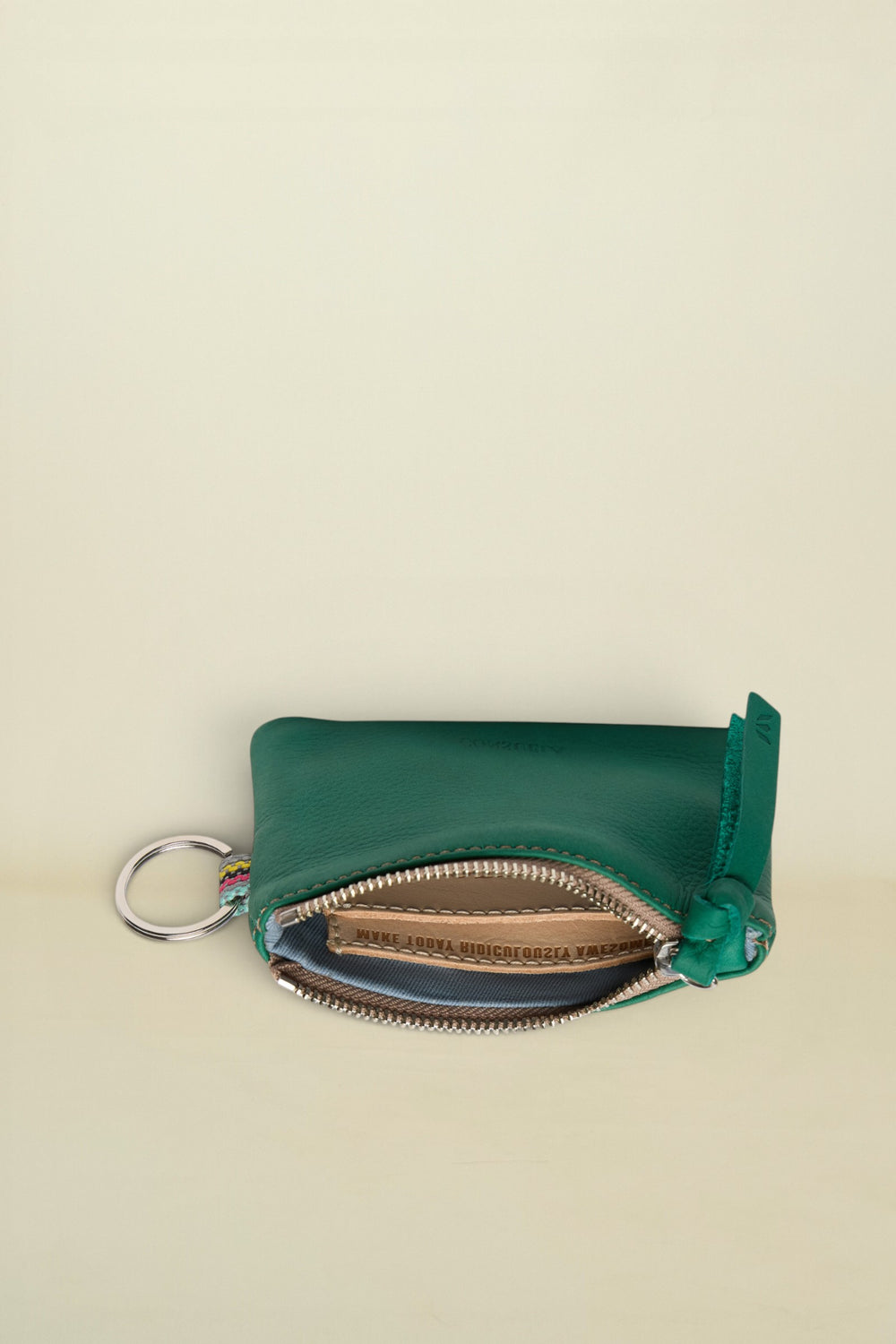 Point of Origin teal leather coin pouch with a silver zipper, key ring, and colorful woven detail