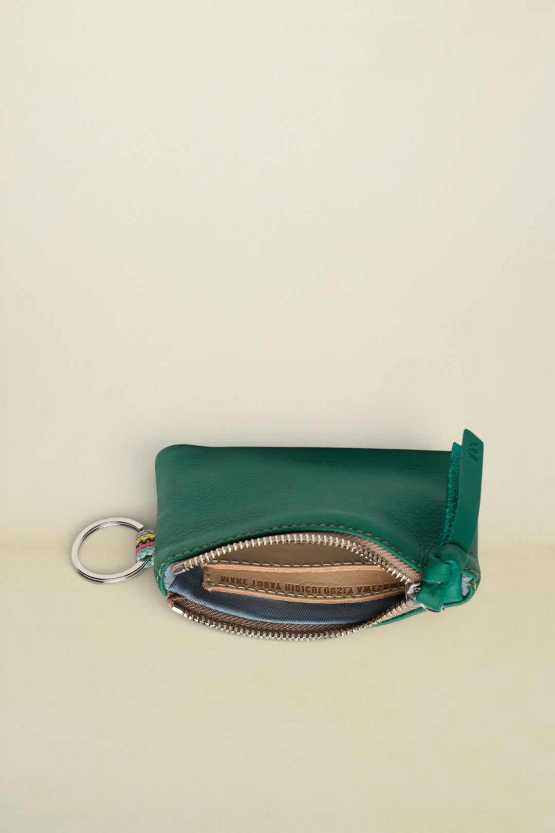 Point of Origin teal leather coin pouch with a silver zipper, key ring, and colorful woven detail