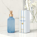 Point of Origin Volcano Caffè Capri room spray in a blue glass bottle with gold sprayer next to its striped box.