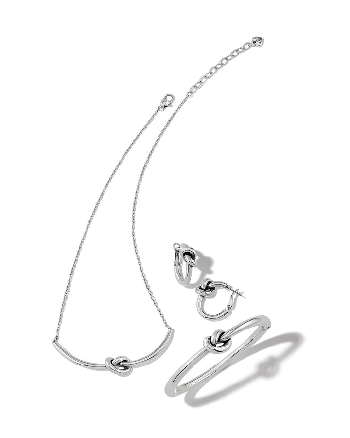 Silver necklace, bracelet, and ring set on a white background
