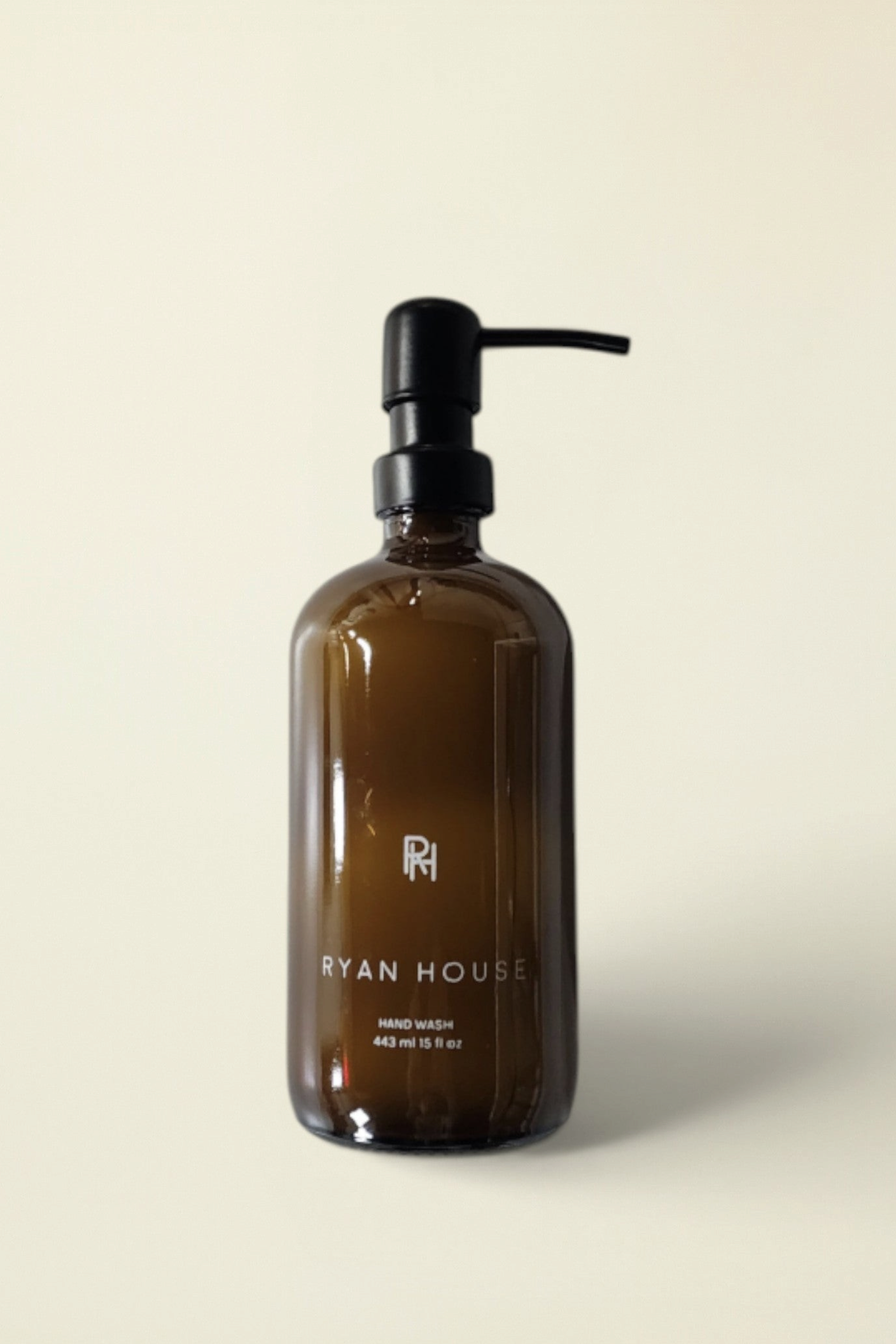 Ryan House hand wash in an amber glass bottle with a black pump dispenser, set against a solid cream background.