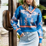 Woman wearing a blue patterned sweater and denim skirt outdoors.