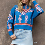 Woman wearing a blue patterned sweater and denim skirt against a brown background
