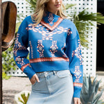 Woman wearing a blue patterned sweater and denim skirt outdoors.