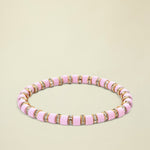 Pink beaded bracelet with gold accents on a white background