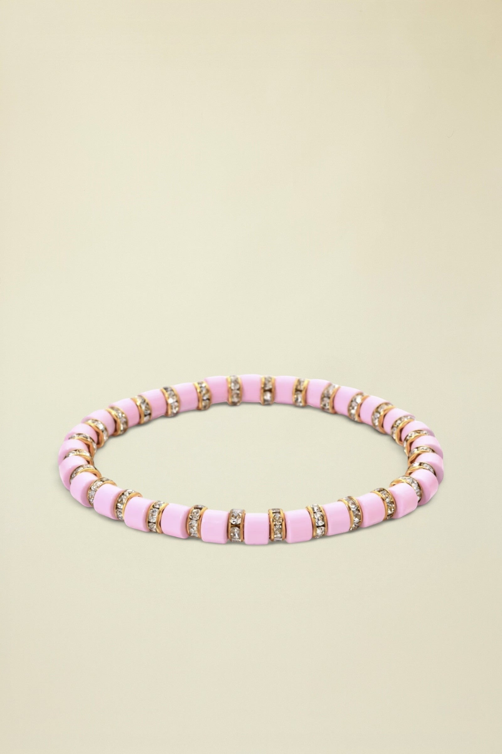 Pink beaded bracelet with gold accents on a white background