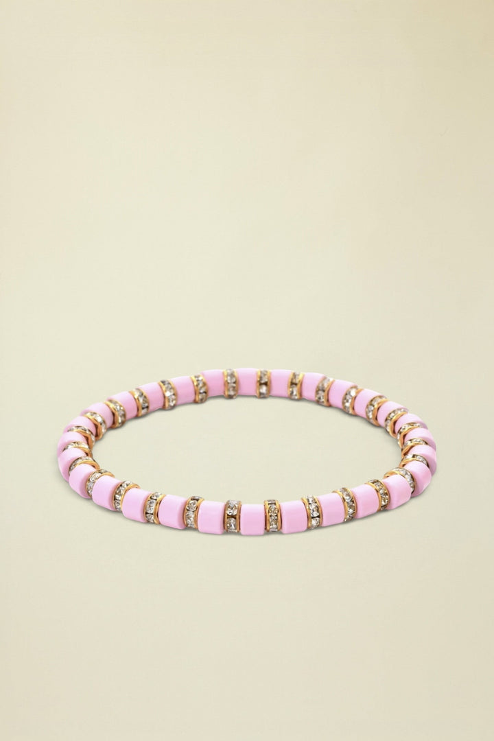 Pink beaded bracelet with gold accents on a white background