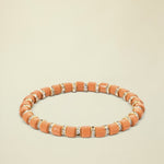 Orange beaded bracelet with small crystals on a white background