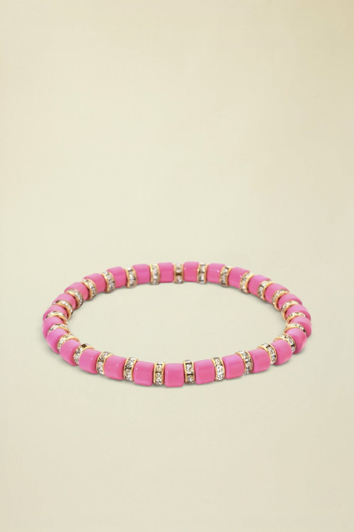 Pink beaded bracelet with gold and clear accents on a white background