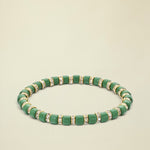 Green beaded bracelet with gold accents on a white background