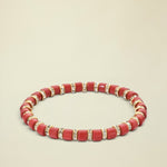 Red beaded bracelet with gold accents on a white background