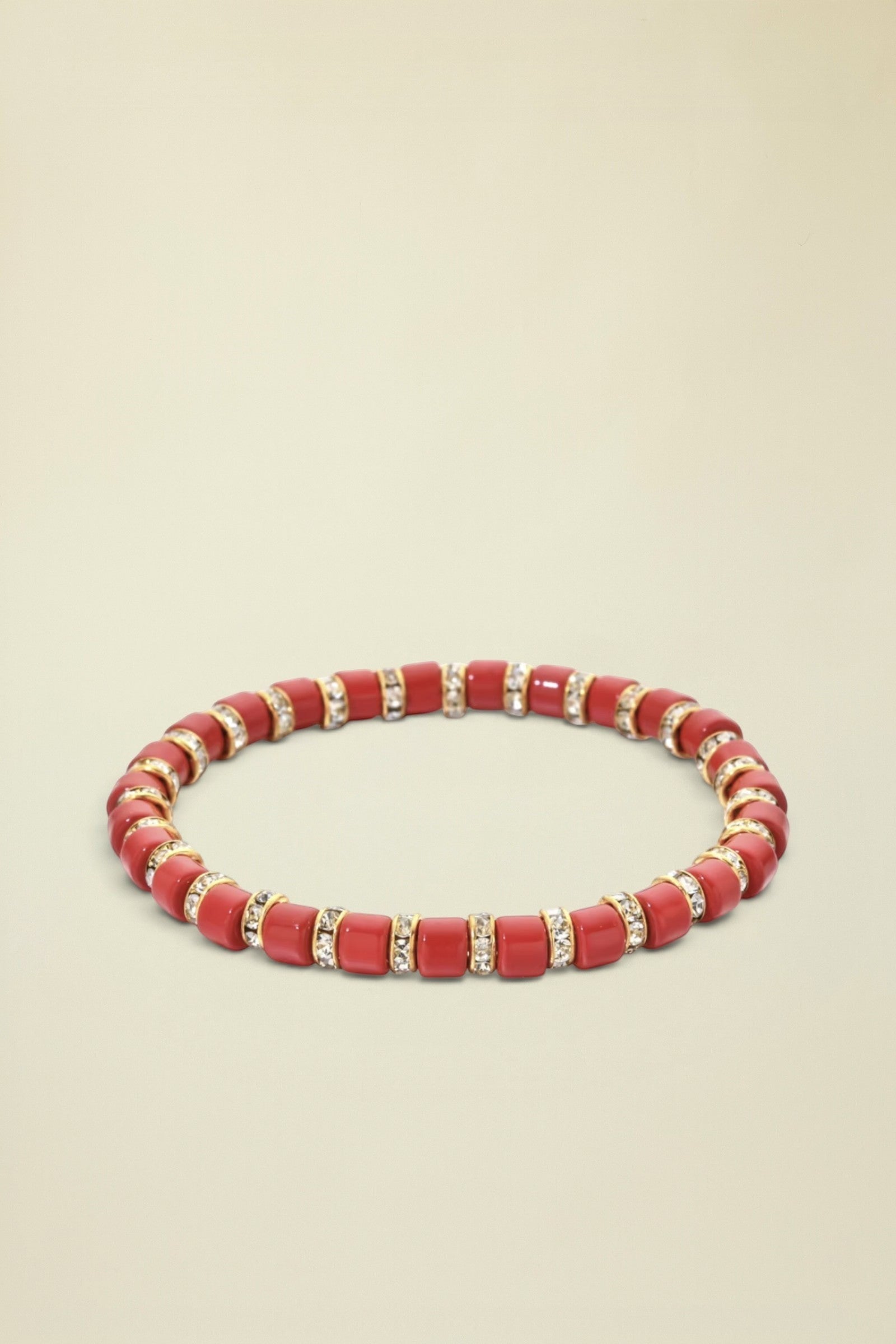 Red beaded bracelet with gold accents on a white background