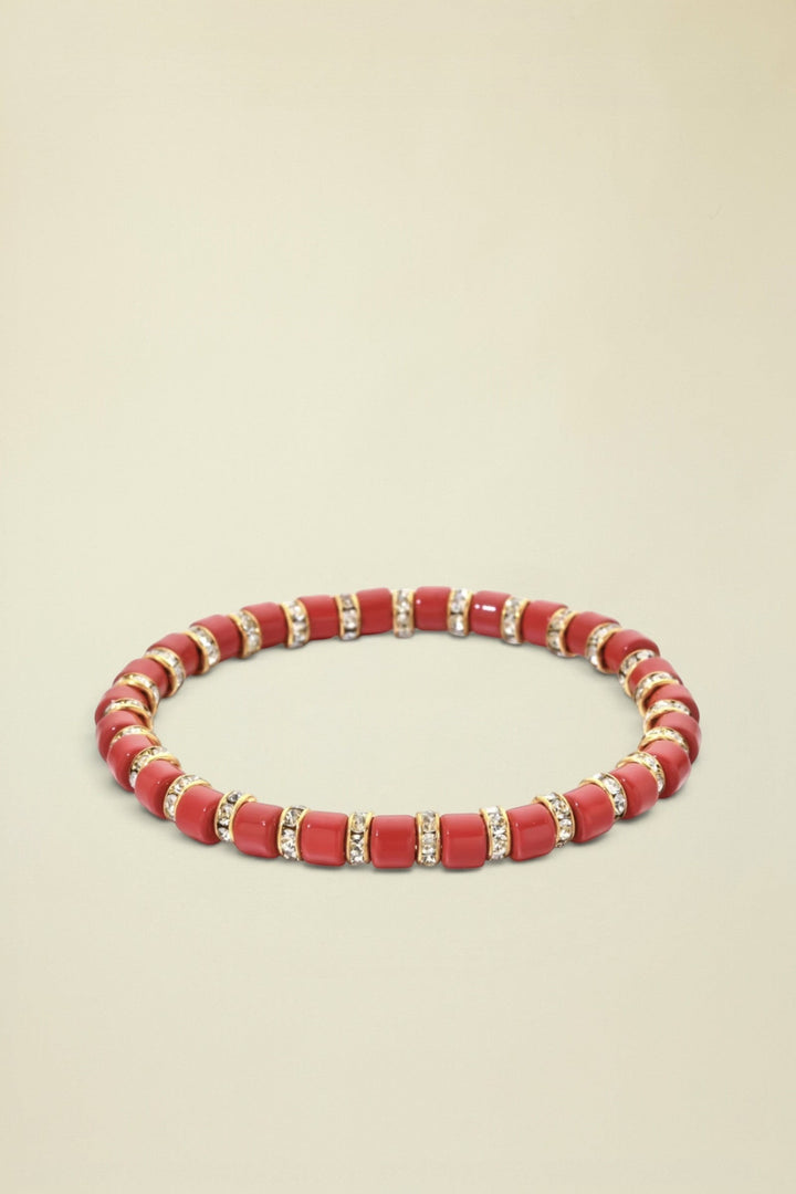 Red beaded bracelet with gold accents on a white background