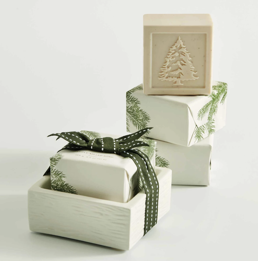 Gifts wrapped in white paper with green ribbons and tree designs on a white background