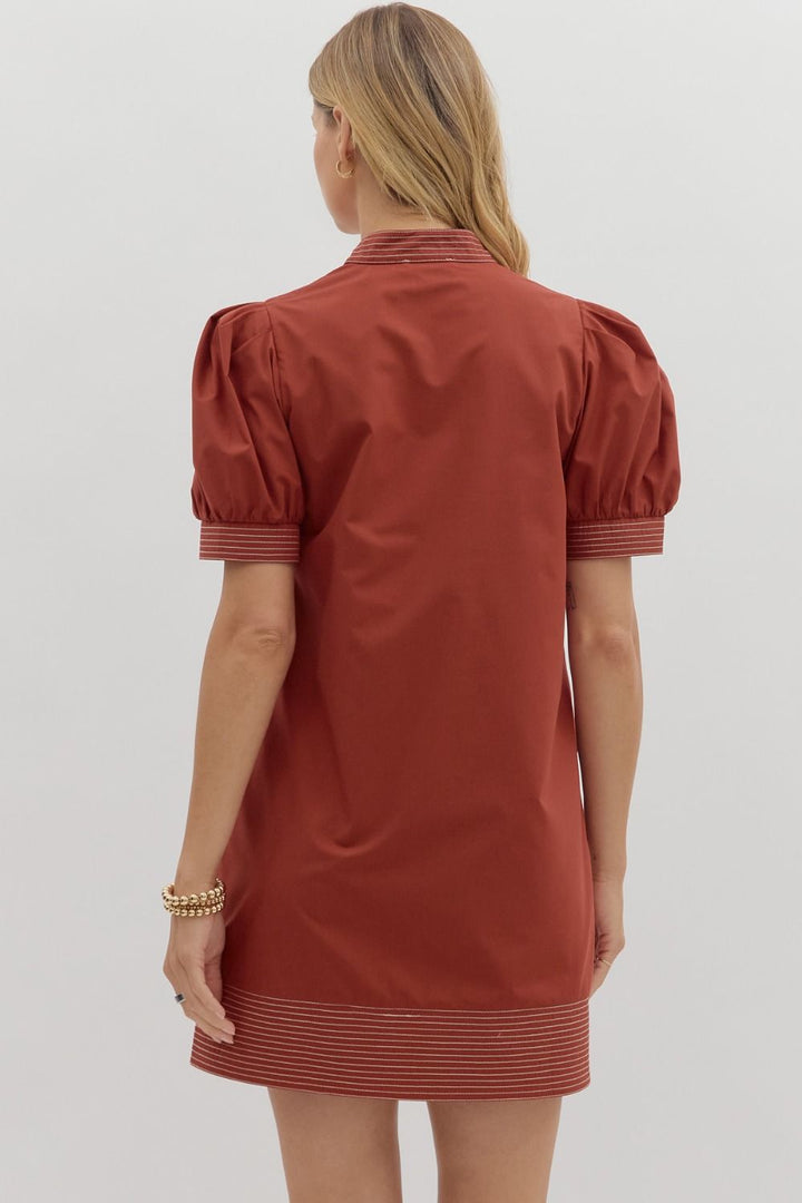 Woman wearing a rust-colored dress with puff sleeves on a white background