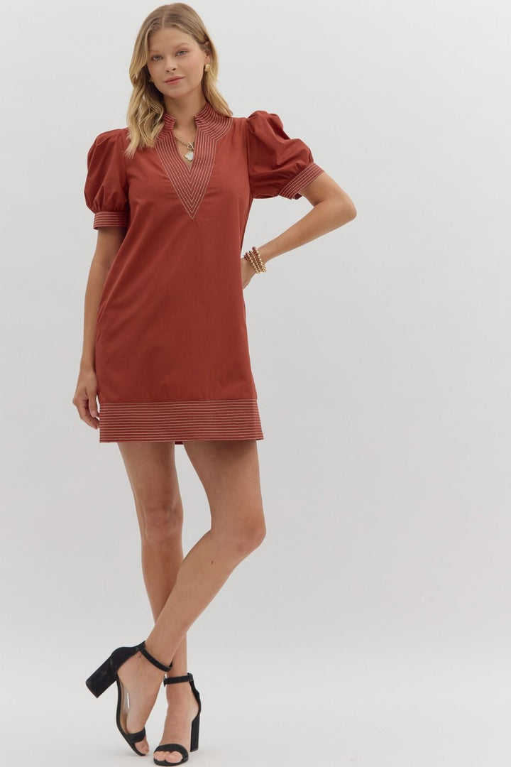 Woman wearing a rust-colored dress with puff sleeves on a white background