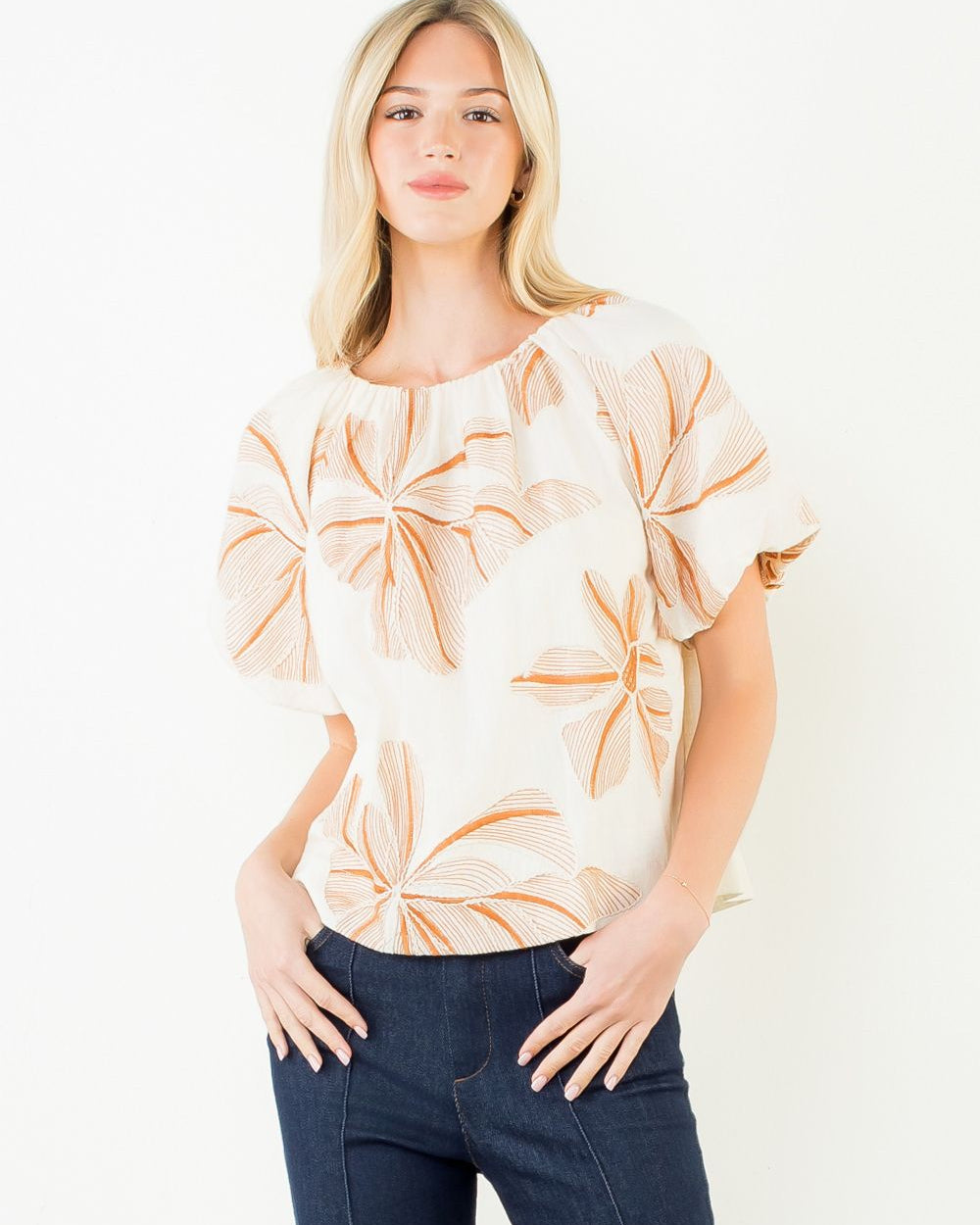 Woman wearing a floral blouse and dark pants on a white background